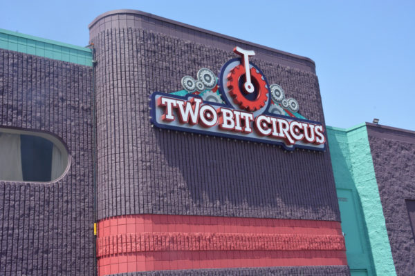 Top of Two Bit Circus facade with "Two Bit Circus" signs and unicycle logo