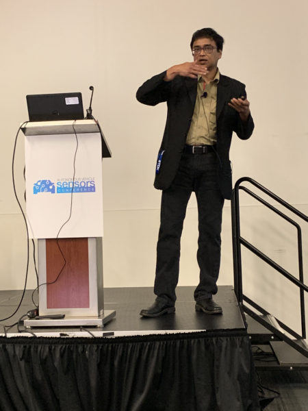 Manju Hegde uses both hands to illustrate how his company's technology consolidates radar functions on one chip during Autonomous Vehicle Sensors Conference