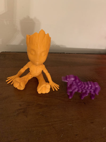3D printed tree character sits near 3d printed purple unicorn on a shelf