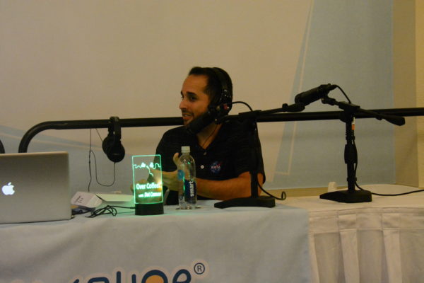 StangSat software mentor Kelvin Ruiz discusses the project as he wears headphones and speaks into a mic at the Talkshoe pavilion