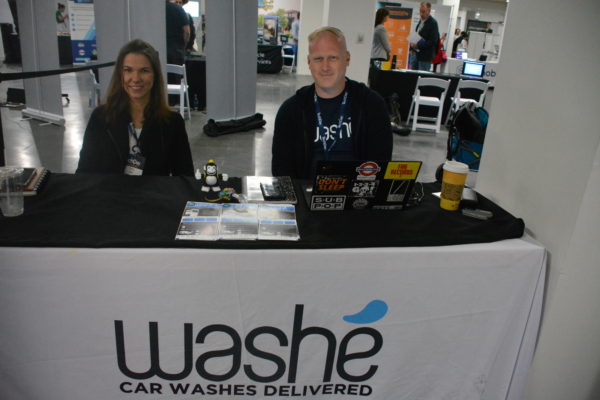 Staffers sit at table with Washe and "car washes delivered" on their tablecloth