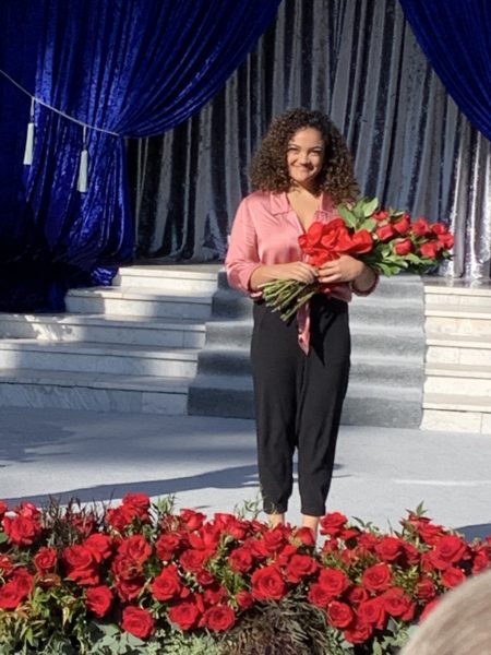 Laurie Hernandez stands with bouquet of red roses on stage