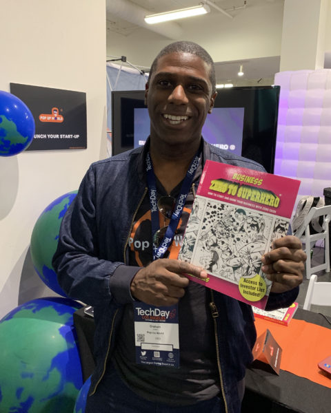 Graham Jules smiles as he displays his book next to his Pop Up World exhibit at TechDay LA 2019.