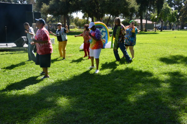 Reverend KC and worshippers line dance on sunlit green lawn at SGV Pride 2019