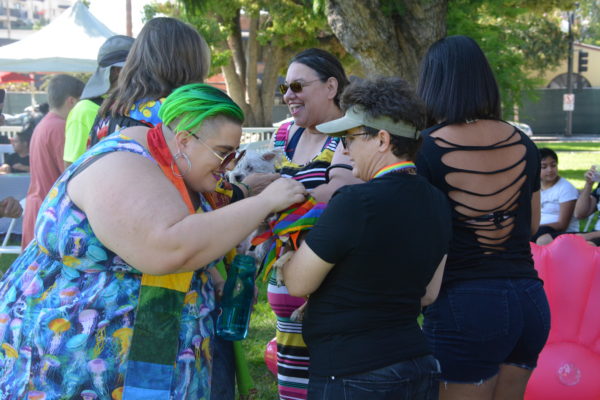 Reverend KC leans forward to bless a small dog ina woman's arms at San Gabriel Valley Pride
