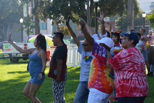 San Gabriel Valley Pride attendees dance and wave their hands in the air