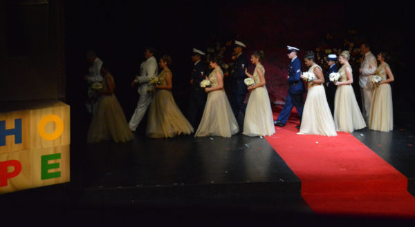 New Rose Queen® Camille Kennedy and Royal Court leave the stage, each on the arm of a uniforned escort