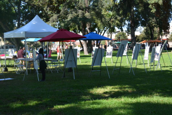Volunteers set posters of LGBT student athletes on easels in sunlit Central Park for SGV Pride Festival