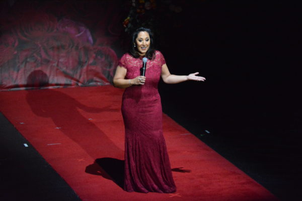 Lynette Romero gestures as she speaks from onstage with mic in her hand at Rose Queen® coronation