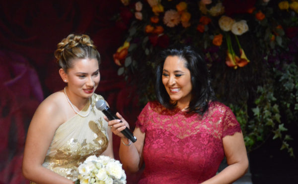 MIa Thorsen speaks into mic as Lynette Romero laughs during Rose Queen® coronation program