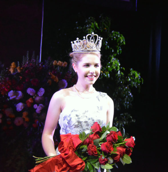 102nd Rose Queen® Camille Kennedy holds bouquet of red roses and smiles for the camera