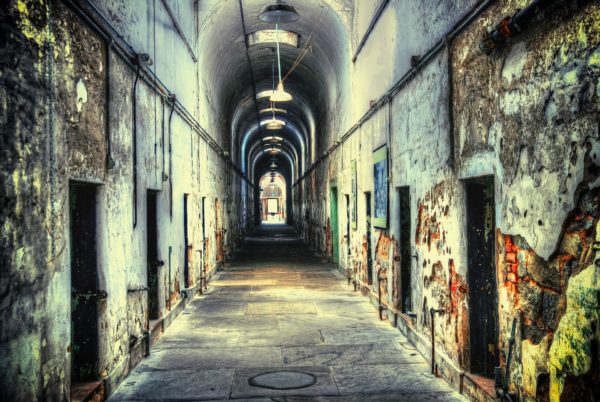 Creepy abandoned corridor with doors on either side and graffiti on walls