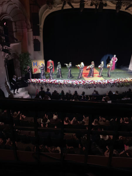 Mariachi Divas ensemble leave the stage playing their instruments as audience claps along during Rose Queen® coronation program