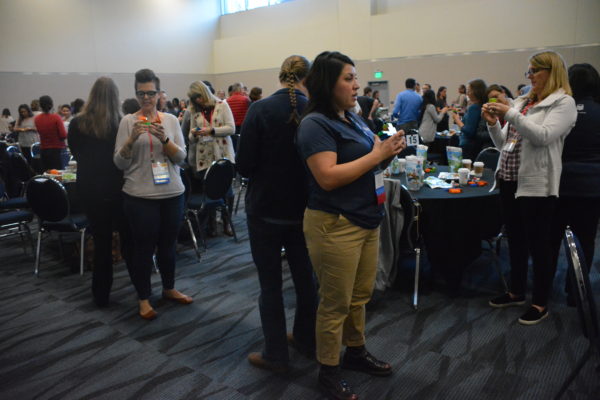 Teachers stand in back-to-back pairs while creating LEGO structures