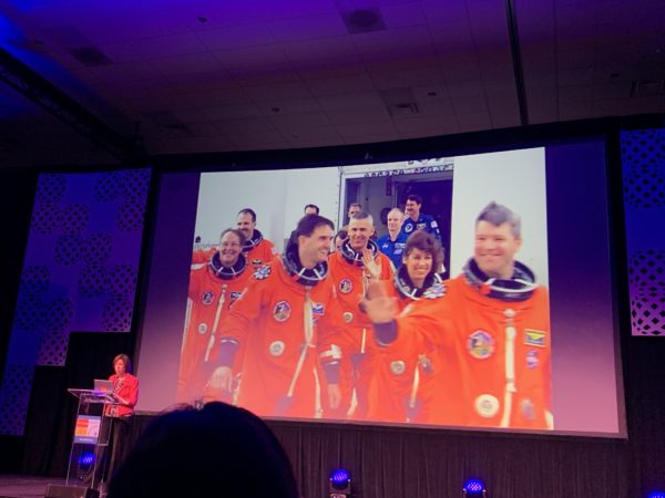 Dr. Ellen Ochoa displays slide of herself with Atlantis crew as she speaks from the lectern at California STEAM Symposium 2019