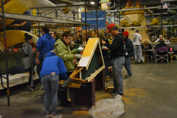 Volunteers glue gold seeds to the sun's "rays" for the Dole Packaged Foods float