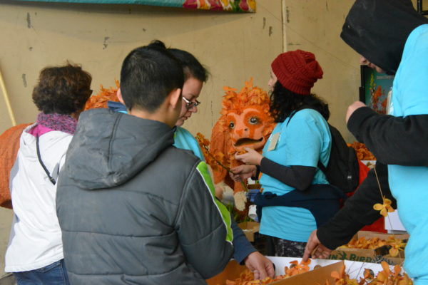 volunteers paint glue on a golden lion's face near the UPS Store float