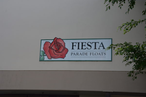 "FIesta Parade Floats" sign with red rose on it