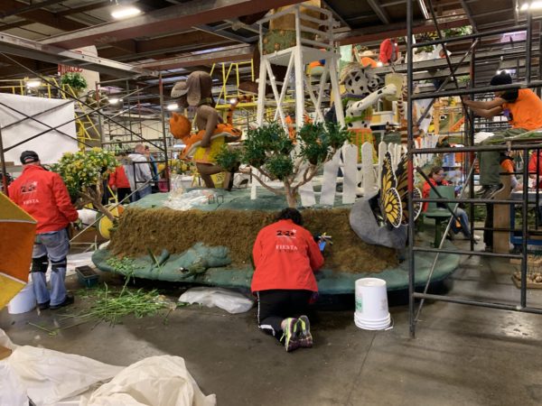 DigAlert float with scaffolding and red-coated Fiesta Parade Floats staff members decorating it