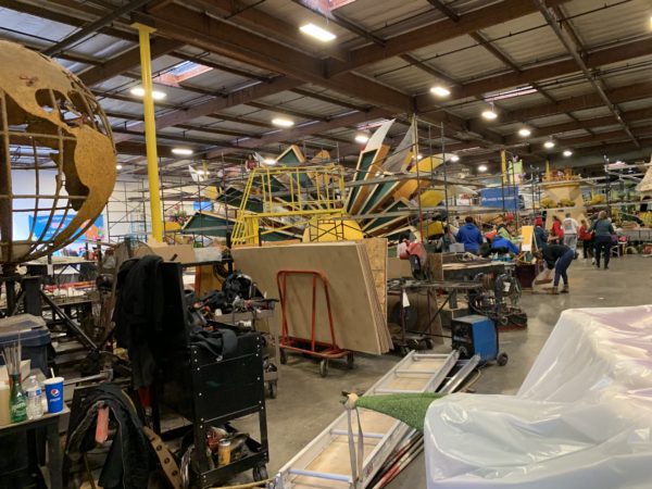 Overview of Fiesta Parade Floats warehouse with three floats being decorated