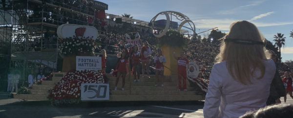 "Bucky", the badger mascot of the University of Madison - Wisconsin team, waves from atop a football float, surrounded by cheerleaders