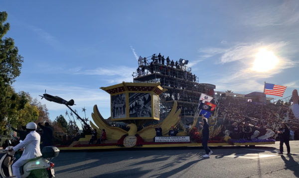 Chinese-American Heritage Foundation float flies American flag from its back and has giant Chinese red-and-gold lantern, with mosaics of Chinese-American war heroes depicted in seed mosaics, near the reviewing stand