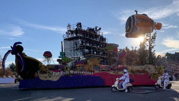Cal Poly "Aquatic Aspirations" float accompanied by White Suiter on motorcycle in parade route