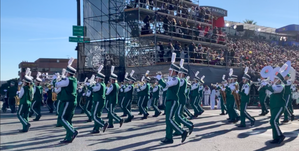 Bandmembers from Puerto Rico's Centenaria Banda Colegial, in green and white uniforms, play brass instruments as they march by the reviewing stand