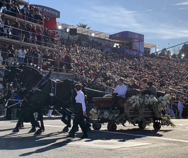 Frozen cast rides in antique sleigh drawn by two black Percherons, past the reviewing stand