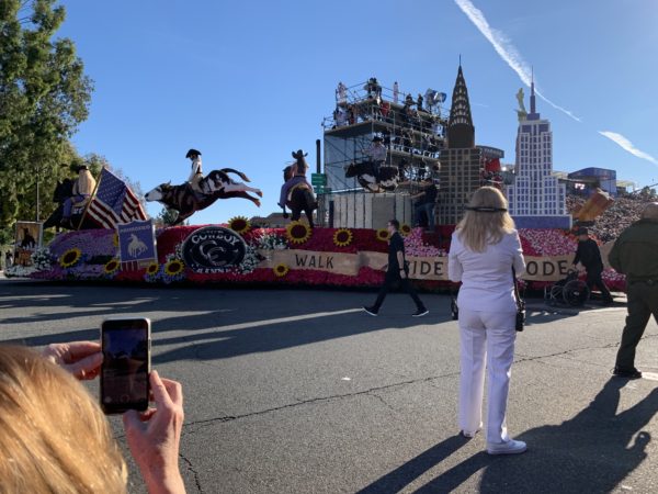 Long shot of "Hope, Ride, Rodeo" float with blonde woman on horse followed by depictions of Empire State Building, Madison Square Garden and a mechanical bull on which a man in cowboy chaps and spurs is riding