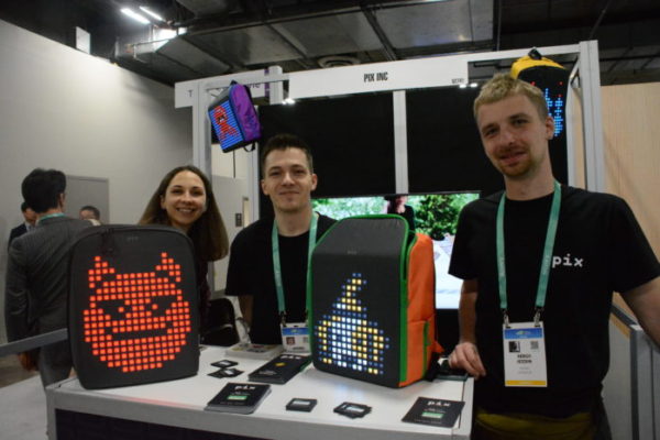 Pix CMO and Co-founder Sergii Ieusdin with staff and light-up bacckpacks with dog and devil designs on them at their Eureka Park exhibit during CES 2020