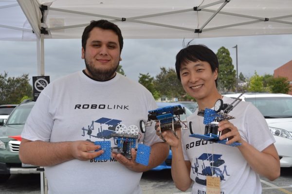 Hansol Hong and Sebastian Sanchez hold up robots their Rokit Smart robotic kit can make at OC Mini Maker Faire, 2015