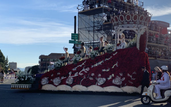 Rose Queen Camille Kennedy and six Royal Court members wave from giant float shaped ike a crown with red rose hearts at the top, next to the reviewing stand