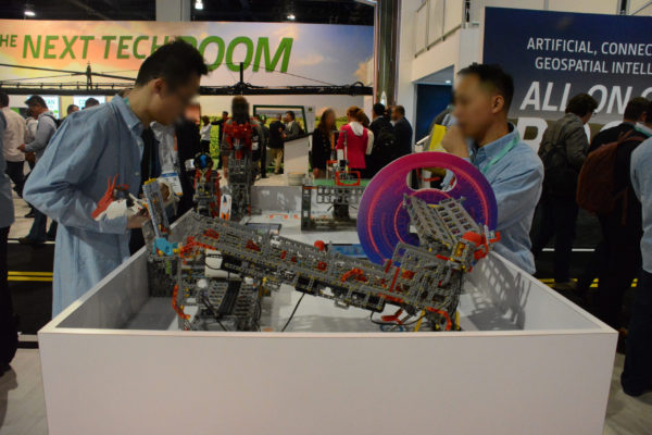 Two UBTECH staffers stand near large Jimu Robot kit "contraption" with red wheel and axle on CES 2020 main show floor