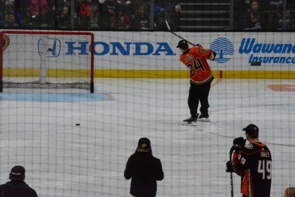 Steel, in orange jersey, hits puck into the net