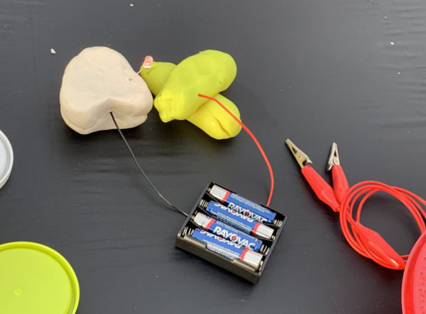conductive Play-Doh attached to bateries by wires near wirecutter on table
