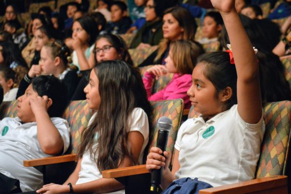 Students raise their hands during LACO "Meet the Music" concert in Santa Monica.