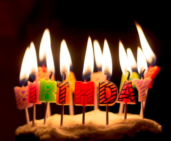 ten birthdya candles flicker above the word "birthday" in wax