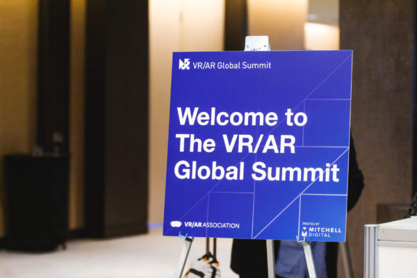 Blue sign on a stand reads, "Welcome to The VR/AR Global Summit".