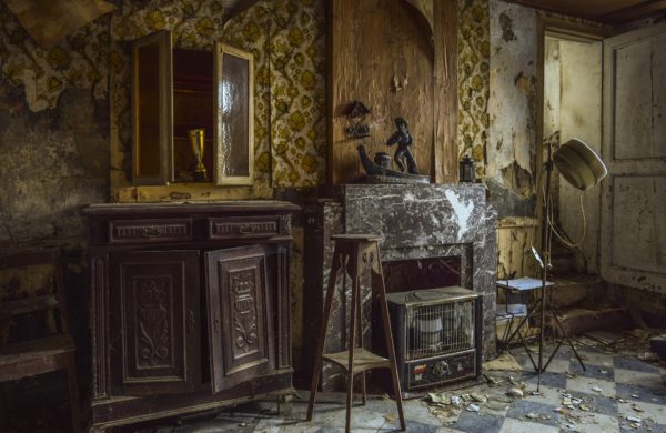 Ancient abandoned room with cobwebs and doors falling off a glass-fronted cabinet