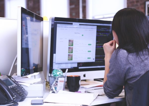 Woman at desk with two computer screens