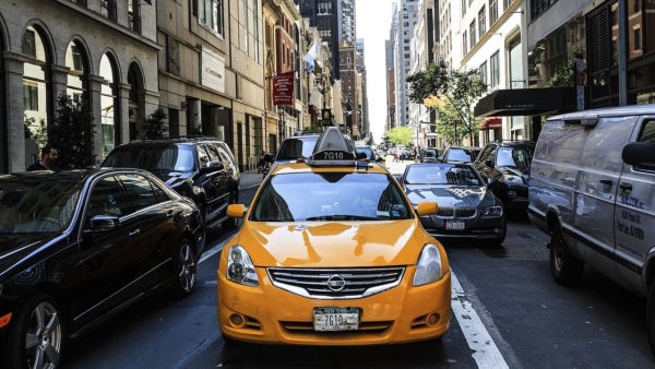 Yellow cab in middle of traffic in downtown Manhattan by day