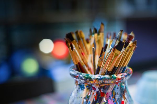 Paintbrushes sit in a glass jar