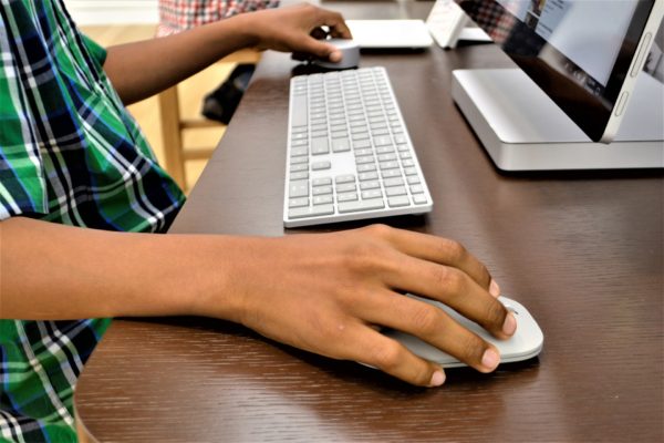 Hands of a Black child operating a computer at a desk