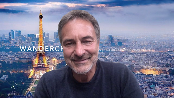Wandercraft Co-Founder/CEO Jean-Louis Constanza smiles before a background of Paris featuring the Eiffel Tower alight and the words, "Wandercraft: Extraordinary Life for Extraordinary People"
