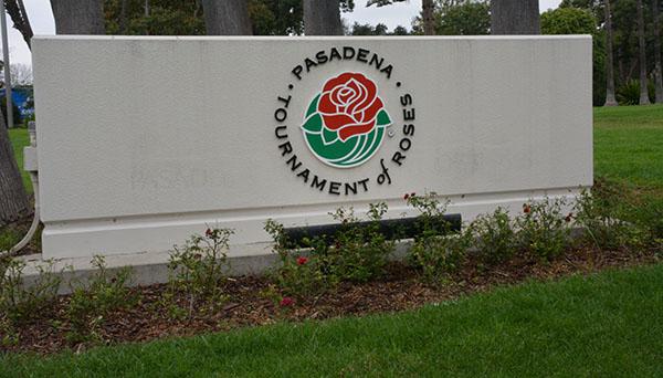 Concrete "Pasadena Tournament of Roses" sign, with the lettering in a circle around a red rose emblem, sits outside Tournament House in Pasadena.