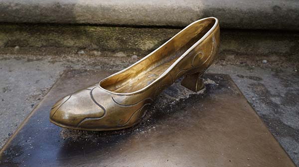 One gold slipper on a paved stone outside a castle