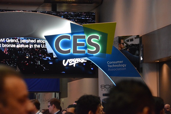 CES attendees walk under a blue and green arch with "CES" on it