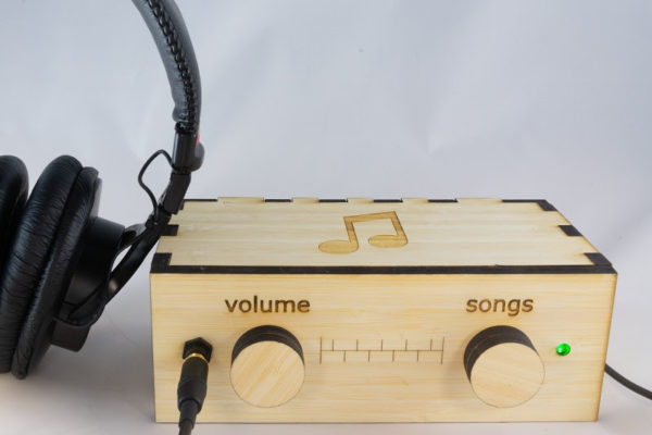 Light wood music player with "Volume" and "Songs" knob and headphones