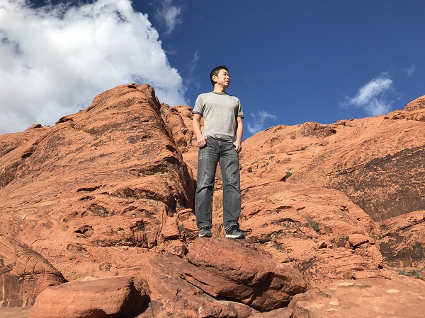 Mynt Sdeno robot creator and Slightech founder Dr. Leo Pang stands on a red rock face against a blue sky with white cumulus clouds